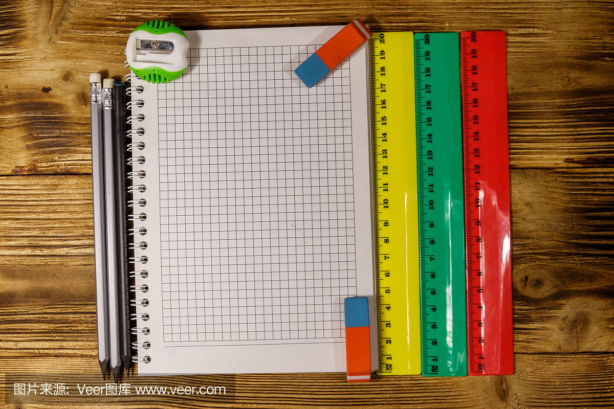 整套學(xué)校文具用品。木桌上的空白記事本、尺子、鉛筆、橡皮和卷筆刀。俯視圖